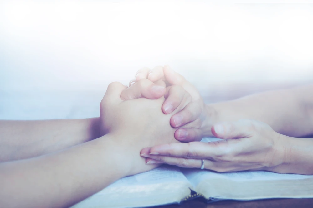 Close up of couple holding hands and praying together