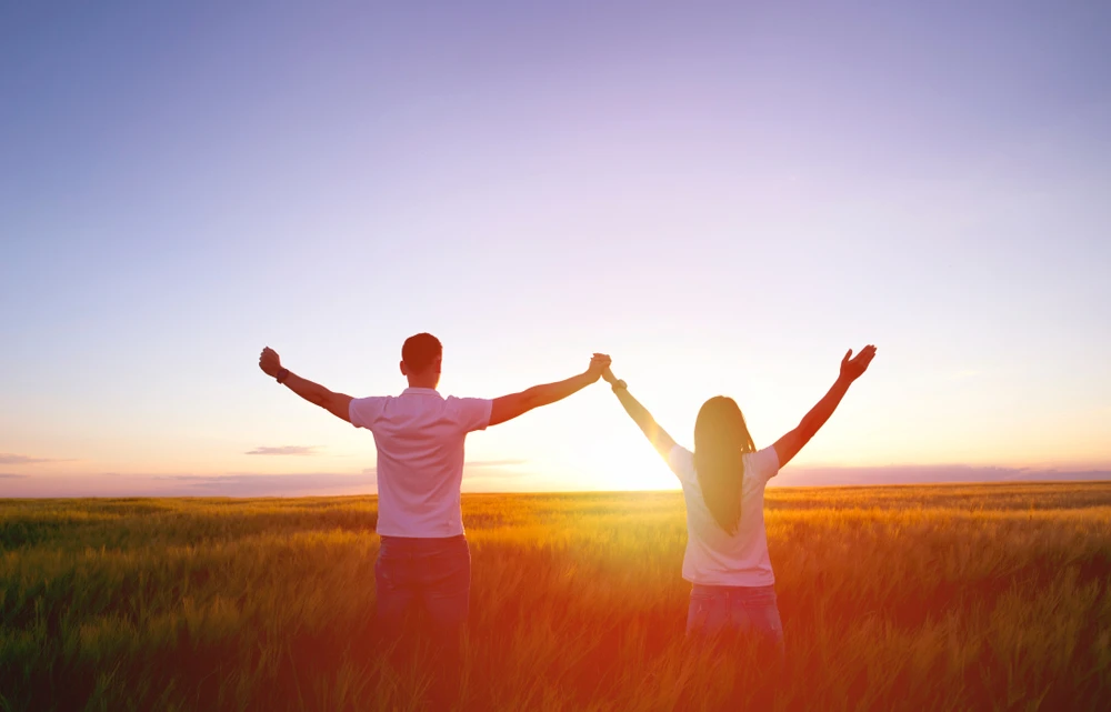 Couple standing in a field during the sunset