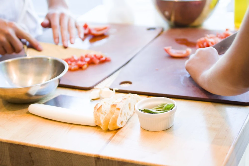 Closeup of two people chopping vegetables in a cooking class